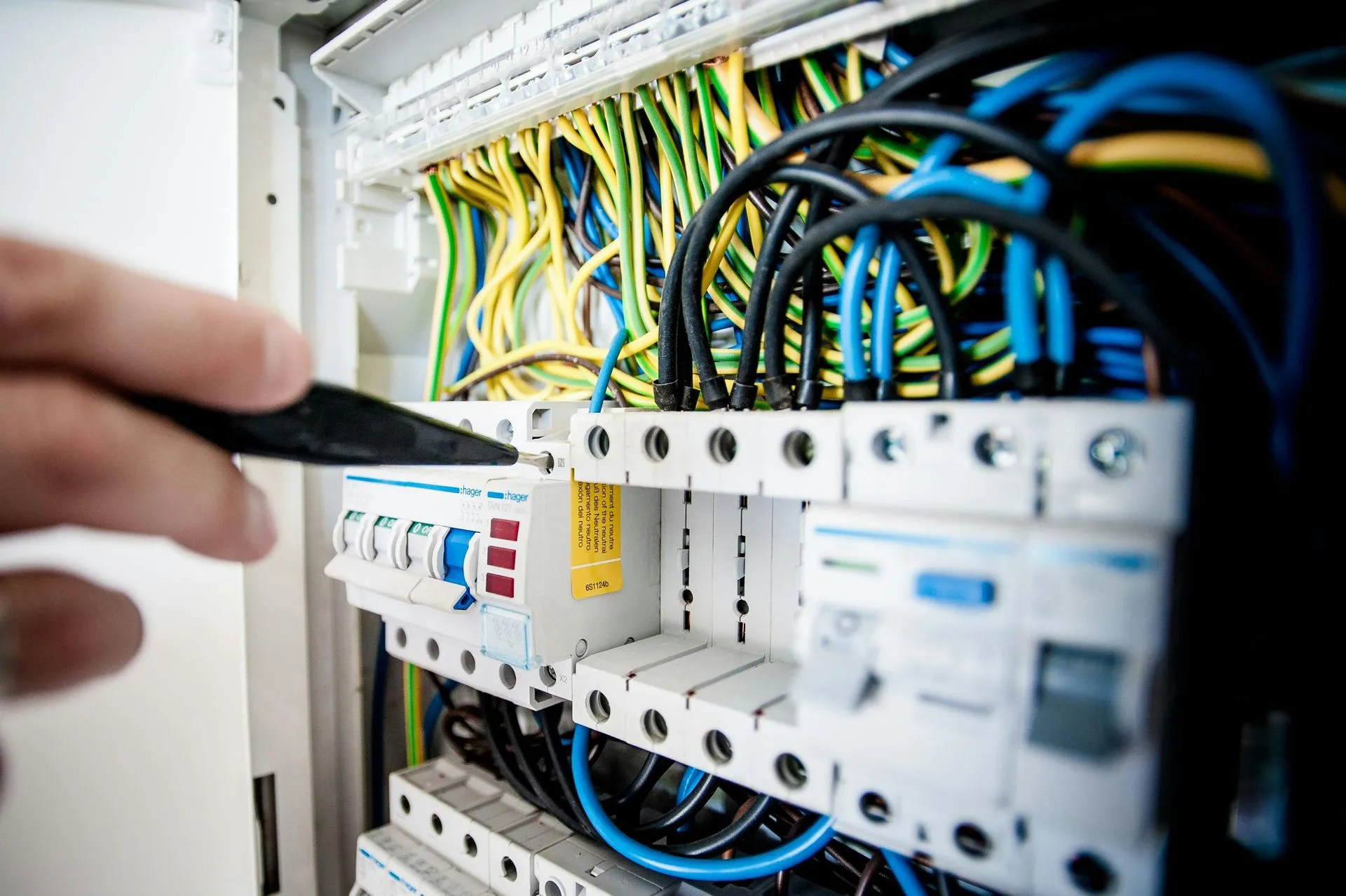 Electrician inspecting electrical panel with colorful wires and circuit breakers.